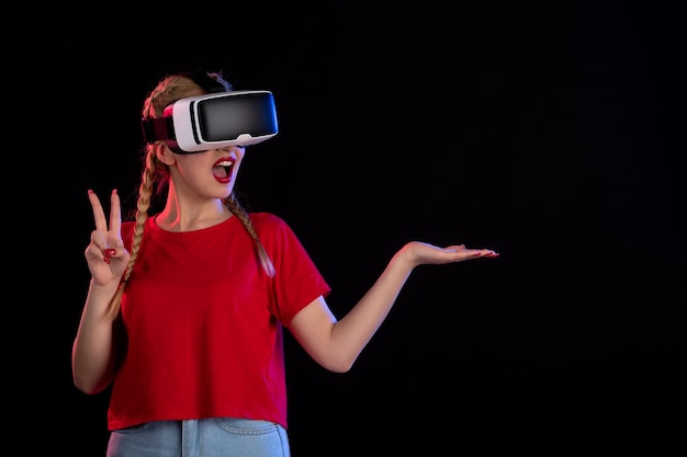 Front view of young female playing vr on dark wall