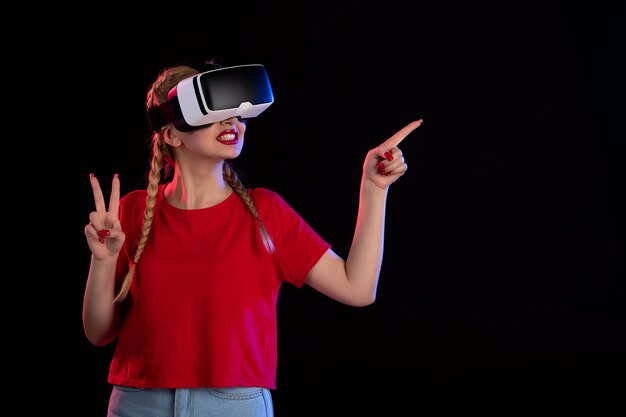 Front view of young female playing vr on dark wall