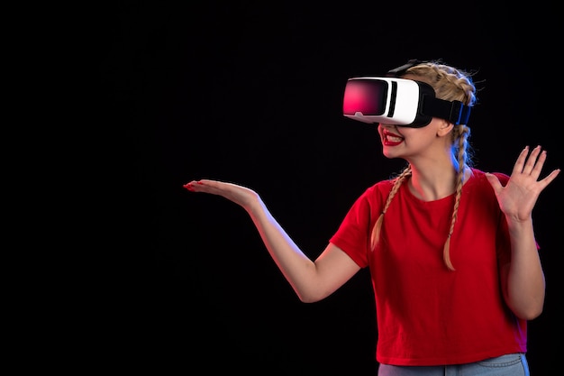 Front view of young female playing vr on dark wall