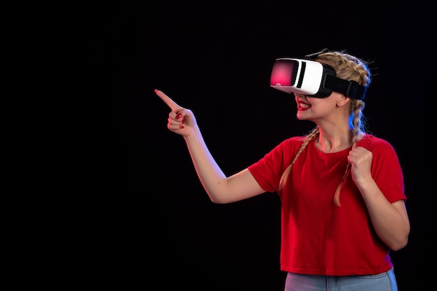 Front view of young female playing vr on dark wall