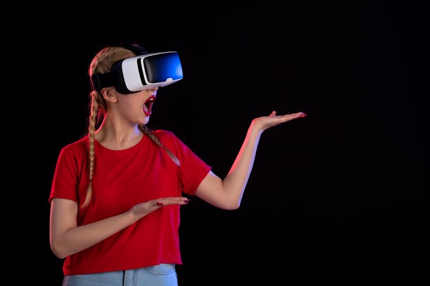 Front view of young female playing vr on dark wall