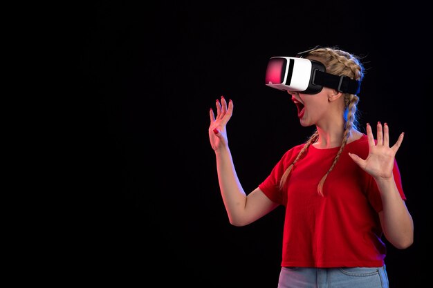 Front view of young female playing vr on dark wall