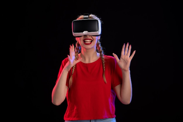 Front view of young female playing vr on dark wall