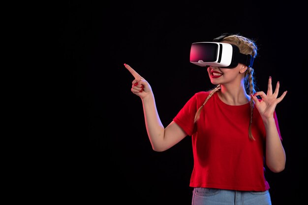 Front view of young female playing vr on dark wall