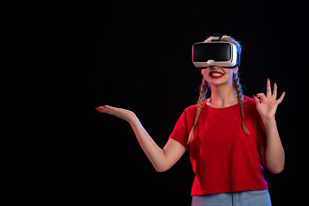 Front view of young female playing vr on dark wall