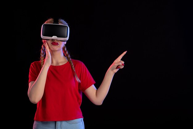 Front view of young female playing vr on dark wall