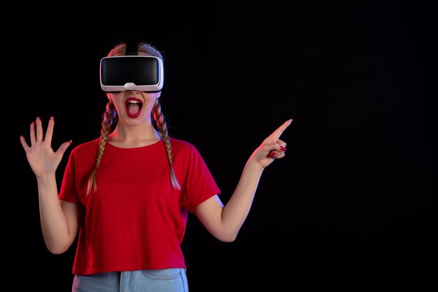 Front view of young female playing vr on dark wall