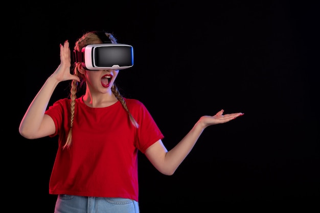 Front view of young female playing vr on dark wall