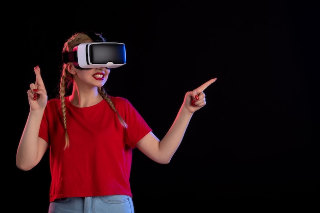 Front view of young female playing vr on dark wall