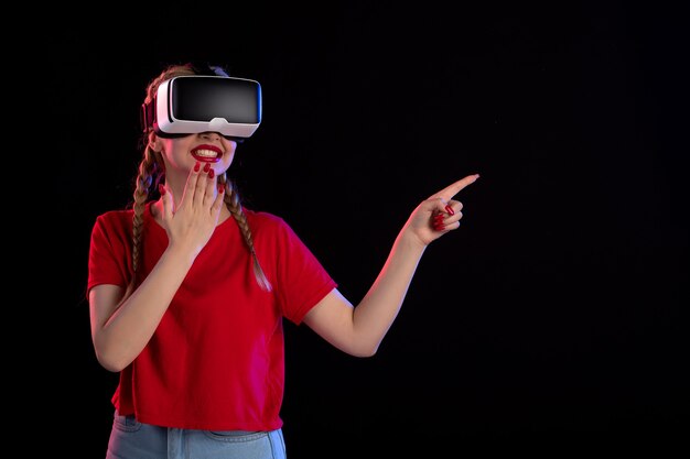 Front view of young female playing vr on the dark wall