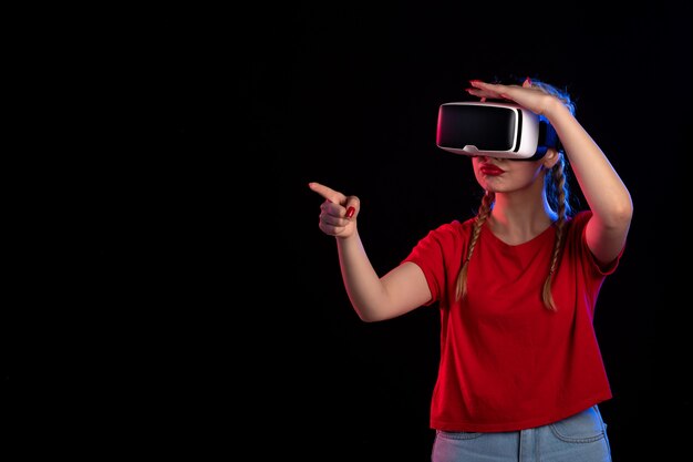 Front view of young female playing vr on the dark wall