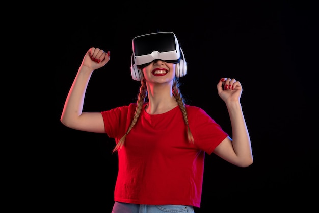 Front view of young female playing vr in headphones on dark  tech game d