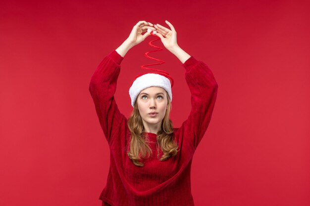 Front view young female playing with her christmas cap on red desk woman holiday red