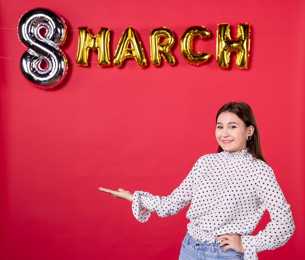 Front view young female posing on march decorated red background passion love horizontal equality feminine affectionate holiday beauty woman