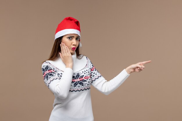 갈색 책상 감정 크리스마스 새 해에 빨간 모자에 포즈 전면보기 젊은 여성