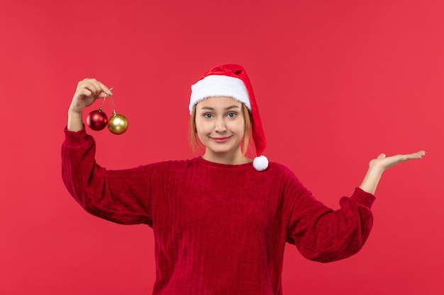 Giovane femmina di vista frontale che posa con i giocattoli di natale sull'emozione rossa di natale di festa del pavimento