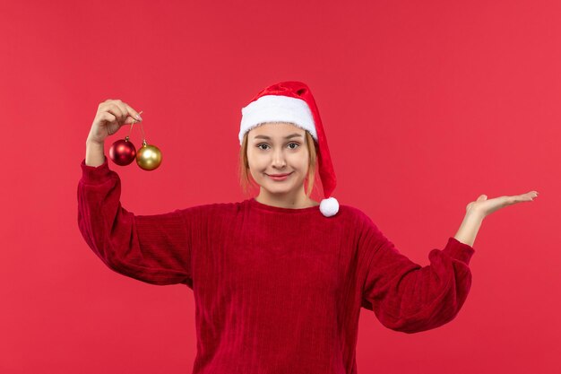 赤い床の休日のクリスマスの感情のクリスマスのおもちゃでポーズをとって正面図若い女性