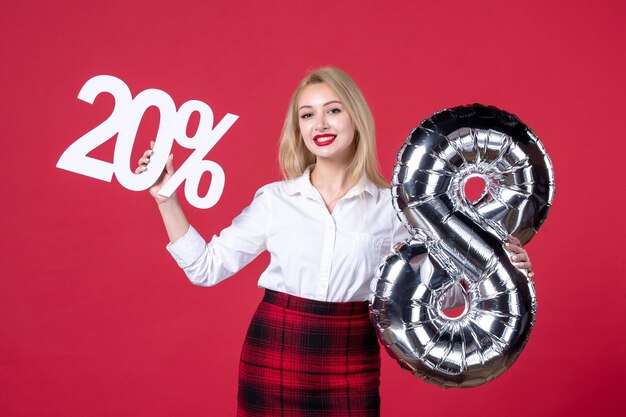 Free photo front view young female posing with silver balloon and on red