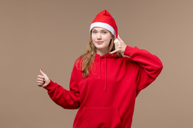 Вид спереди молодая женщина позирует с улыбкой на коричневом фоне рождественские эмоции праздник