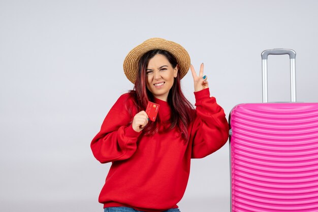 Front view young female preparing for trip and holding bank card on white wall