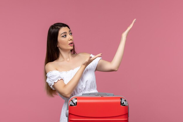 Front view young female preparing for vacation with her red bag on pink desk journey travelling abroad sea voyage trip