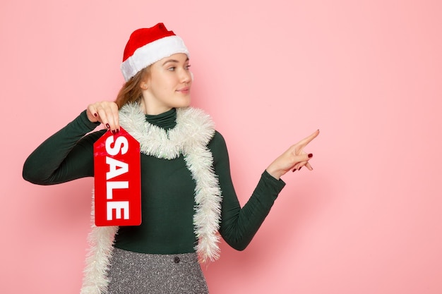 Free photo front view of young female in red cap holding sale writing on pink wall