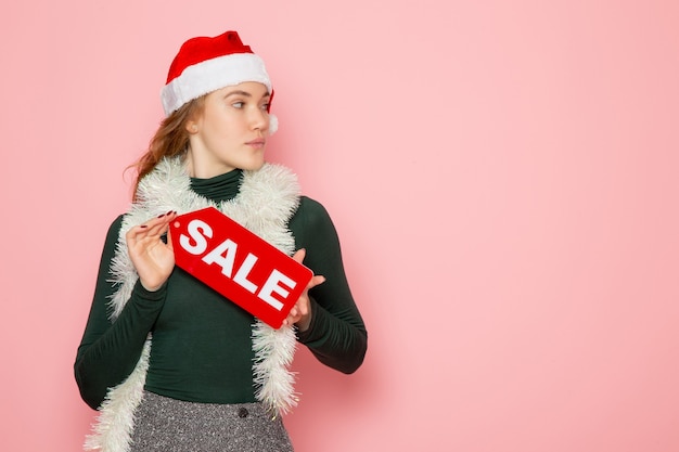 Free photo front view of young female in red cap holding sale writing on pink wall