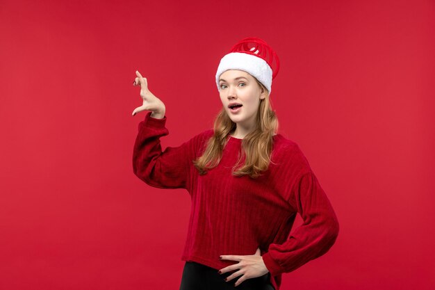 Front view young female in red cap showing size on red desk woman holiday red