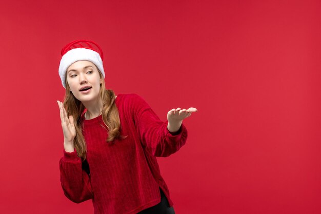 Вид спереди молодая женщина в красной кепке с удивленным лицом на красном праздничном столе
