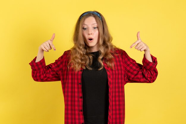 Front view young female in red checkered shirt just standing and posing on yellow background girl human color model woman