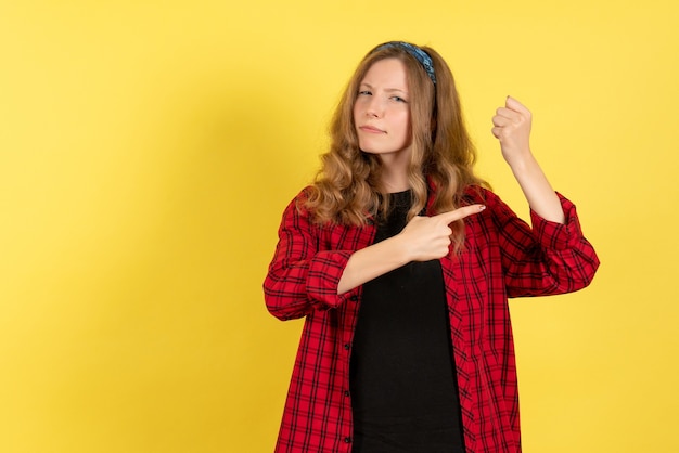 Front view young female in red checkered shirt just standing and posing on yellow background model girls woman color emotions human