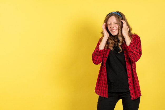 Front view young female in red checkered shirt just standing and posing on yellow desk model girls woman color emotions human