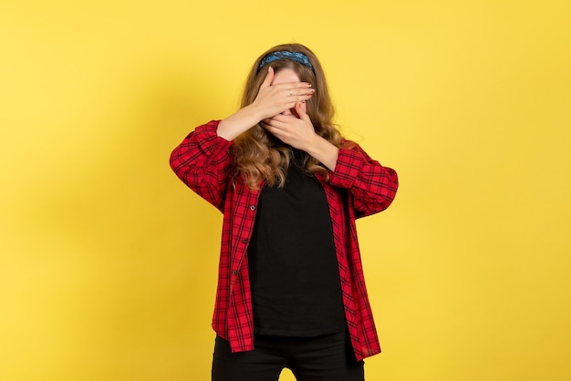 Front view young female in red checkered shirt posing covering her face on yellow background model girls woman color emotions human female