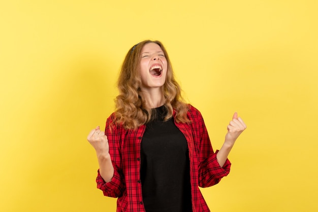 Vista frontale giovane femmina in camicia a scacchi rossa in posa e gioia su sfondo giallo colore umano modello donna emozione