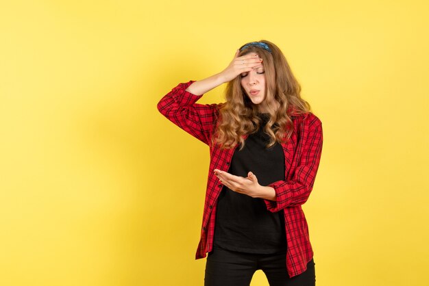 Front view young female in red checkered shirt posing with depressed expression on yellow background human color woman emotion model