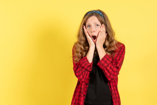 Vista frontale giovane femmina in camicia a scacchi rossa in posa su sfondo giallo ragazze emozioni colore modello umano donna