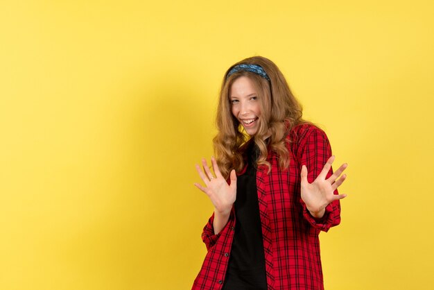 Front view young female in red checkered shirt standing and posing on the yellow background color woman model human girl