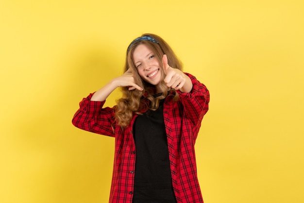 Front view young female in red checkered shirt standing and posing on the yellow background girl color woman model human