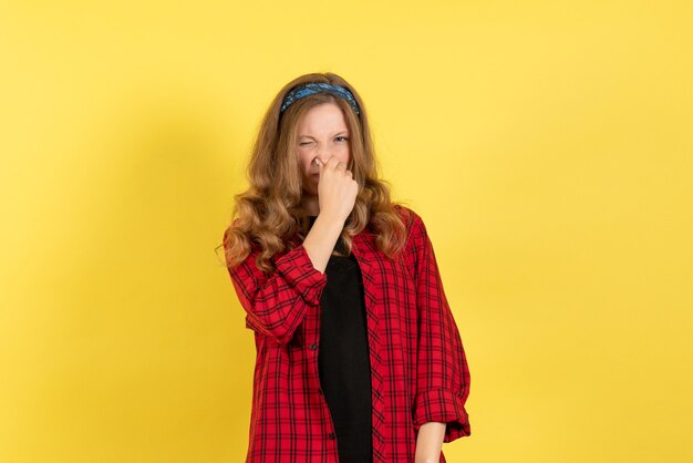 Front view young female in red checkered shirt standing and posing on yellow desk color woman model human girl