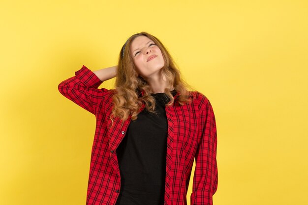 Front view young female in red checkered shirt standing and thinking on yellow background color woman model human girl