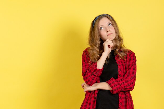 Front view young female in red checkered shirt standing and thinking on yellow background girls human woman color model