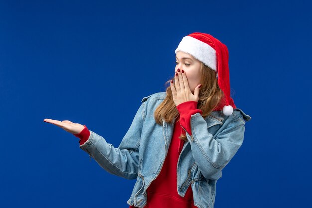 正面図青い背景の上の赤いクリスマスキャップの若い女性クリスマス感情色