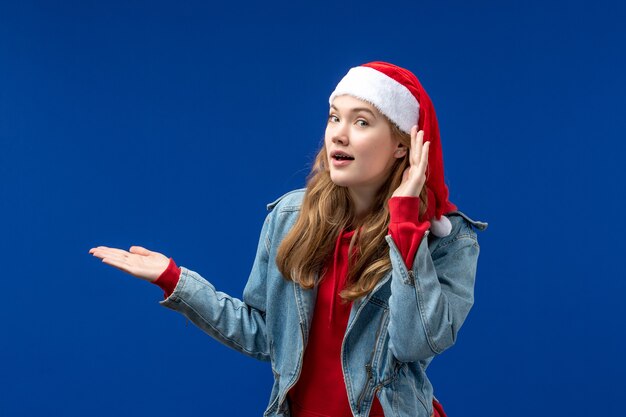 Front view young female in red christmas cap on a blue background christmas emotions color
