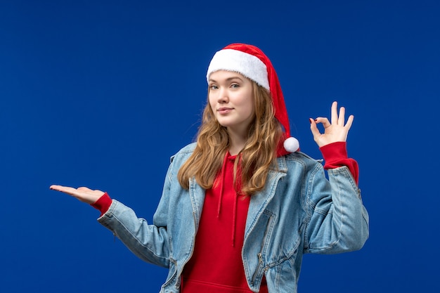 Front view young female in red christmas cap smiling on blue background christmas emotion color