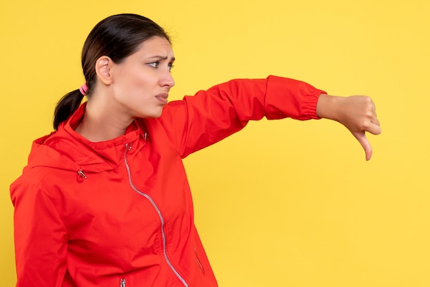 Front view young female in red coat displeased on yellow background