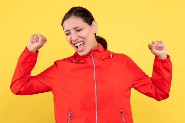 Front view young female in red coat rejoicing on yellow background