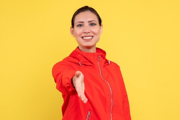 Front view young female in red coat shaking hands on yellow background