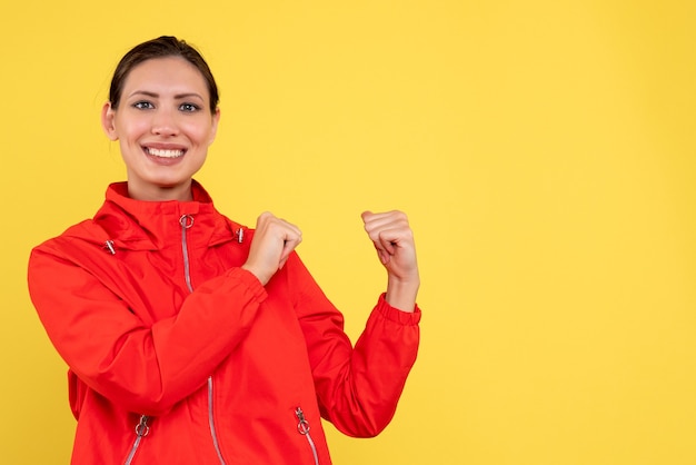 Front view young female in red coat with smile on yellow background