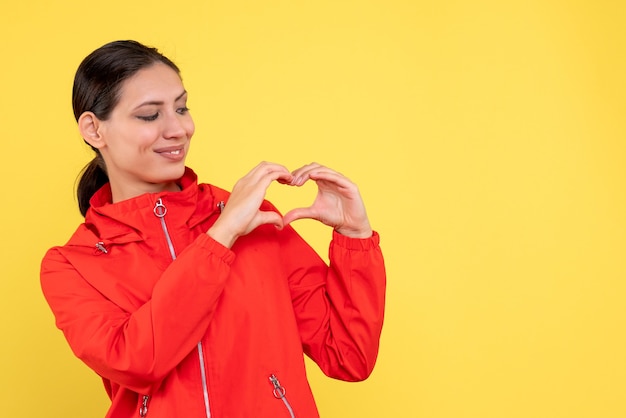 Front view young female in red coat on the yellow background