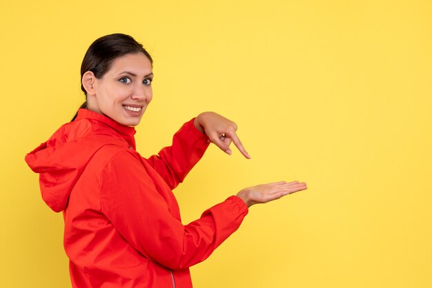 Front view young female in red coat on the yellow background